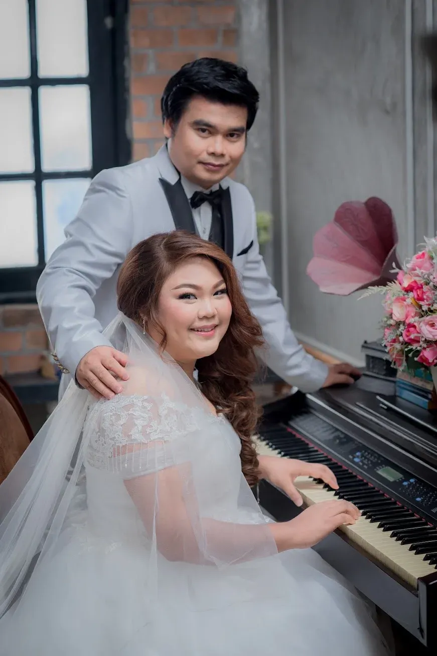 ภาพคู่ของผมและภรรยาในชุดแต่งงานข้างเปียโน